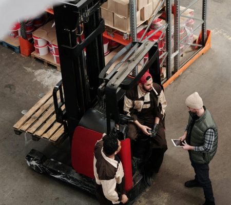 pexels-photo-4483561-4483561 Overhead view of warehouse workers having a meeting with forklift equipment. Collaborative workplace scenario.