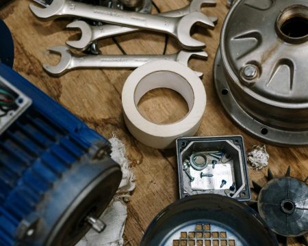 pexels-photo-5532985-5532985 Top view of mechanical parts and tools arranged on a wooden table for repair and assembly.
